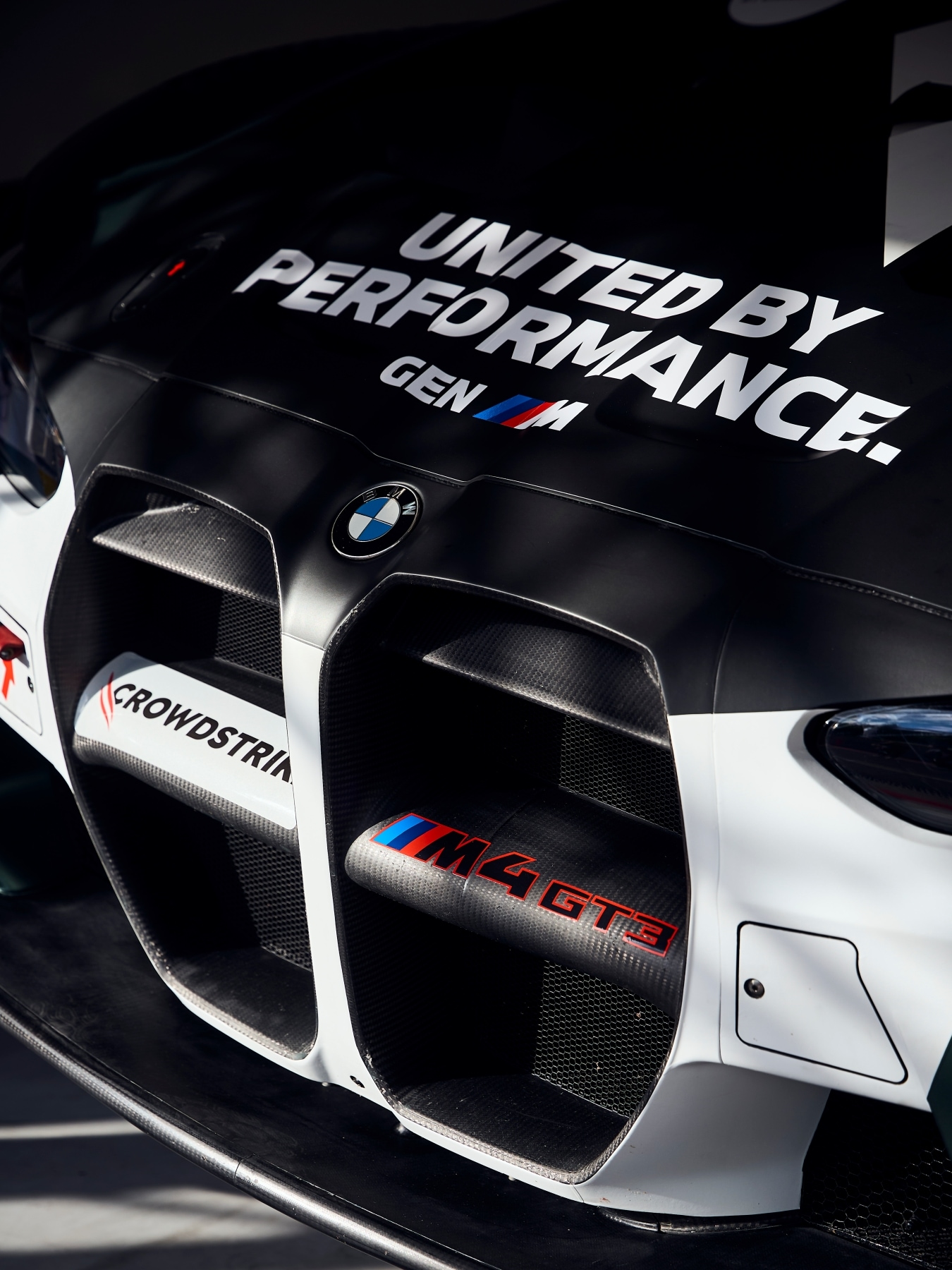Bonnet and front of the BMW M4 GT3 EVO of Rowe Racing with "United by Performance" written on it