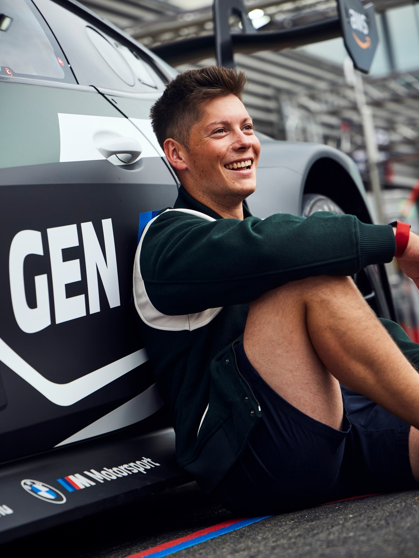 BMW M works driver Max Hesse sitting in front of the BMW M4 GT3 EVO from Rowe Racing with GEN M livery