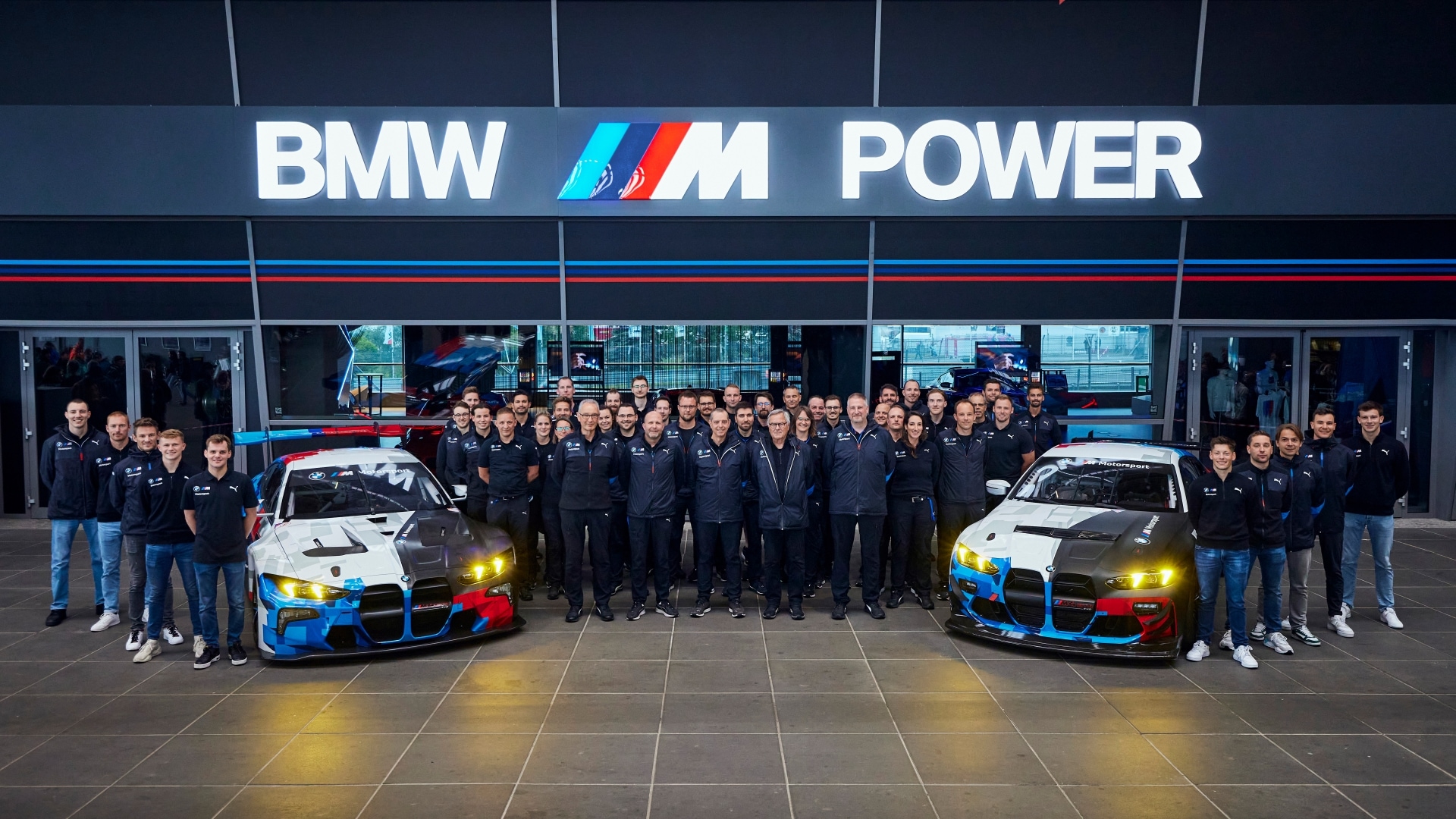 BMW M Motorsport Team with BMW M CEO Franciscus van Meel, the race cars BMW M4 GT3 EVO and BMW M4 GT4 EVO in front of M Showroom at the Nürburgring, Germany