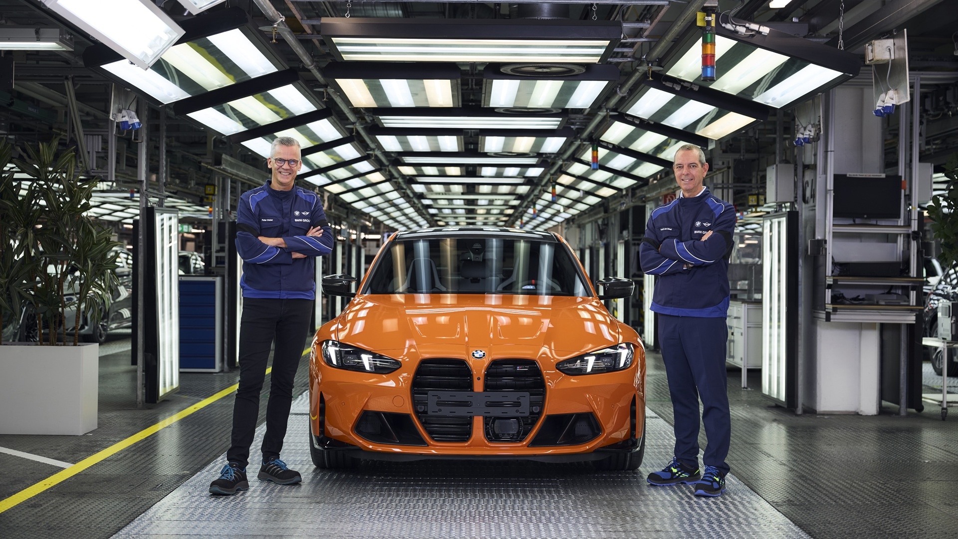 Peter Weber und Franciscus van Meel stehen vor dem millonsten BMW M, einem BMW M3 in Feuerorange.